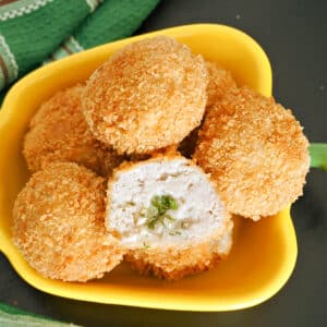 A yellow pepper-shaped bowl with chicken kiev balls.