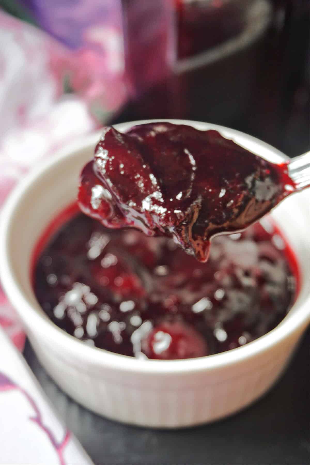 A teaspoon of damson jam over a ramekin of more jam.