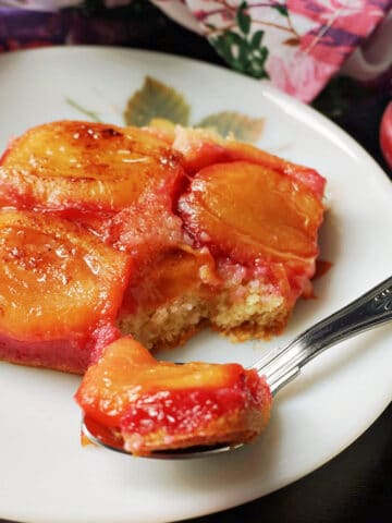 A slice of plum upside down cake on a plate.