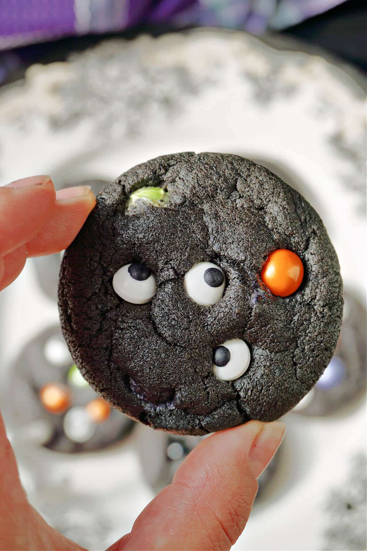 Hand holding a black cookie.