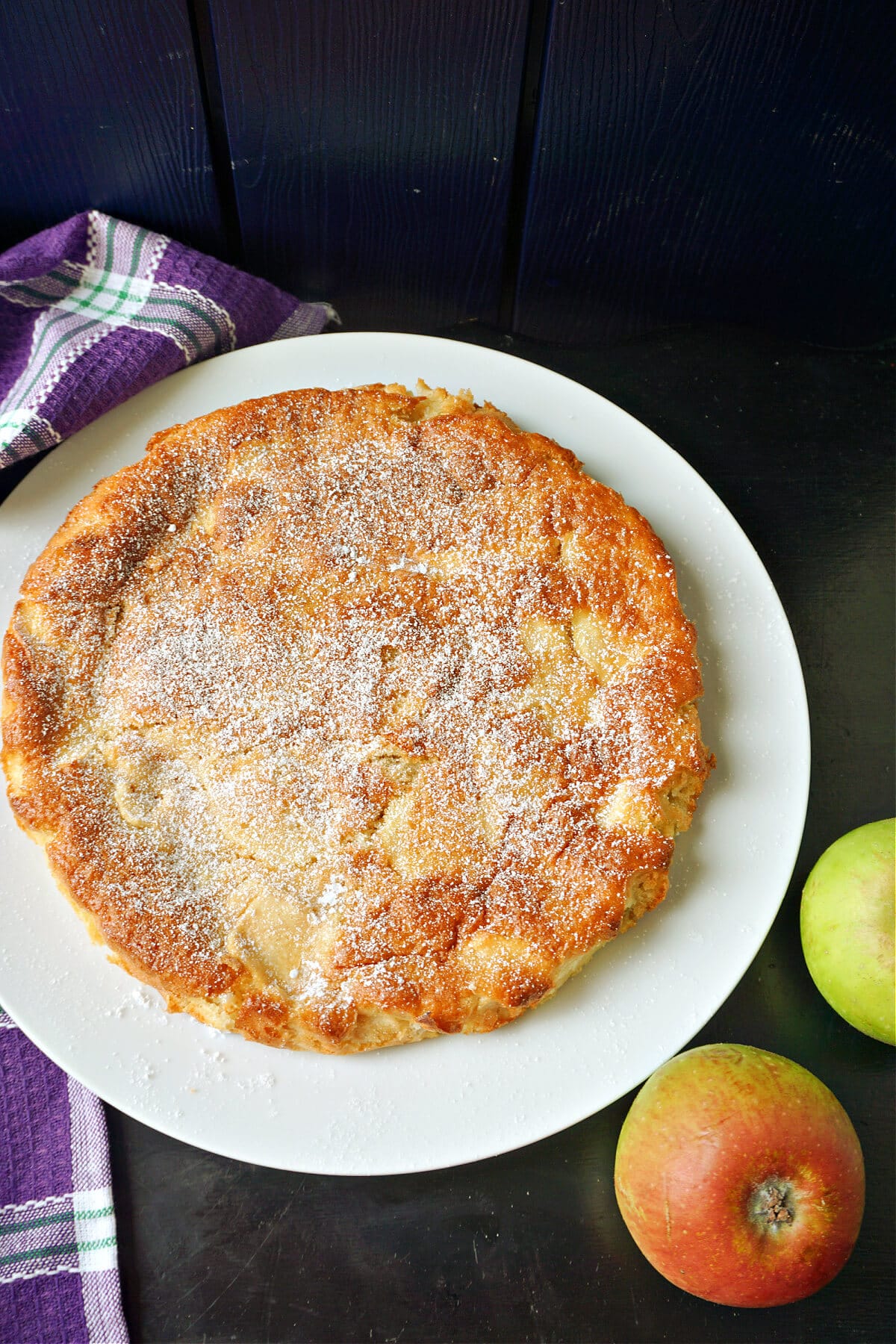 A white plate with an apple cake on it.