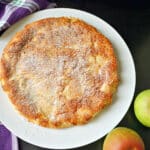 A white plate with a round apple cake.