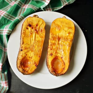 2 roasted squash halves on a white plate.