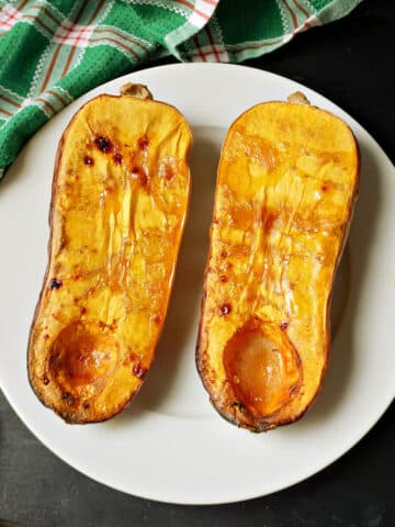 2 roasted squash halves on a white plate.