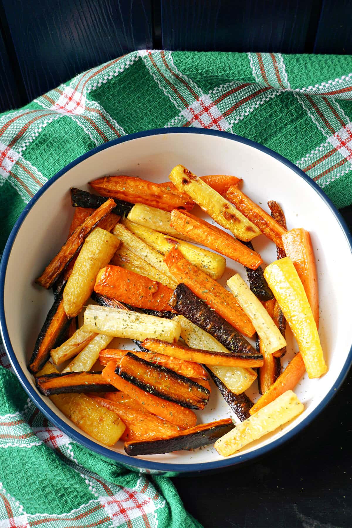 A white bowl with roasted carrots of different colours