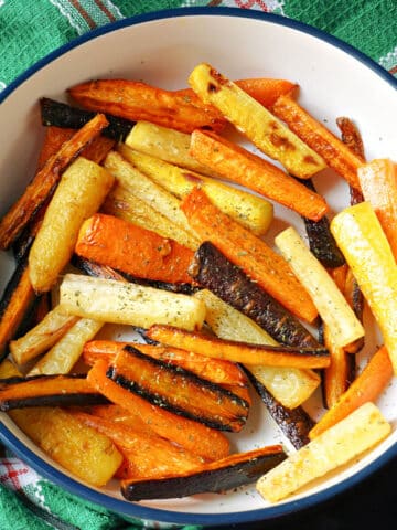 A bowl with roasted carrot sticks in different colours.