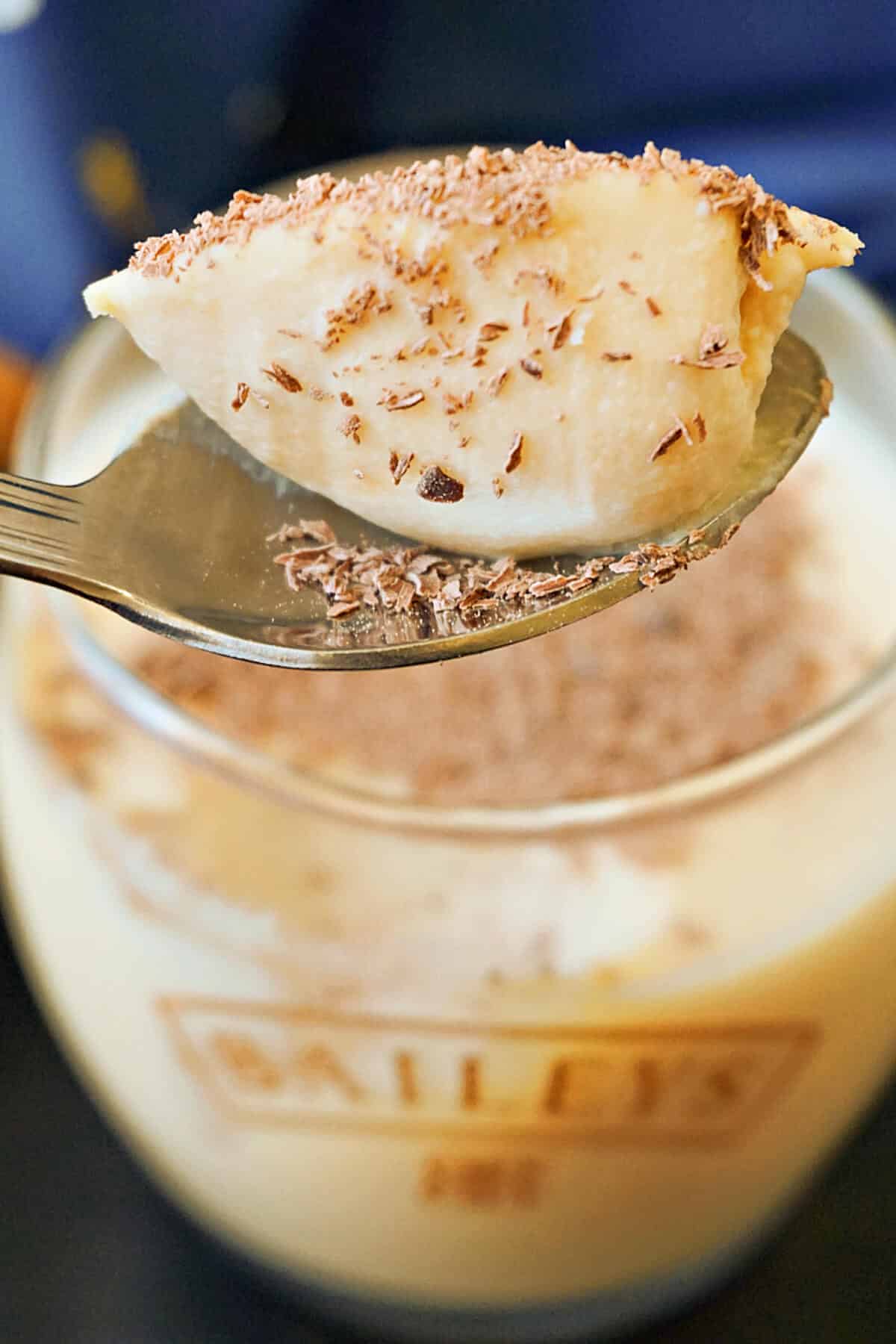 A pot of panna cotta with a teaspoon of dessert.