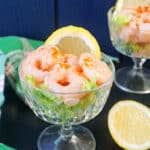 A glass with prawn cocktail and a slice of lemon.