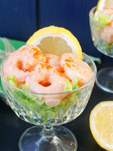 A glass with prawn cocktail and a slice of lemon.