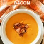A bowl with pumpkin soup garnished with bacon bits.