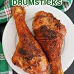 A white plate with 2 turkey drumsticks.
