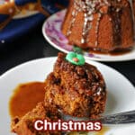 A slice of Christmas sticky toffee pudding with more pudding in the background.