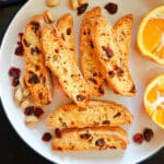 A white plate with 8 biscotti with cranberries, pistachios and orange.