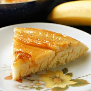 A slice of banana upside down cake on a white plate.