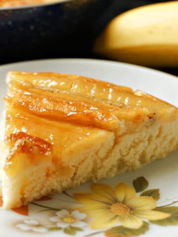 A slice of banana upside down cake on a white plate.