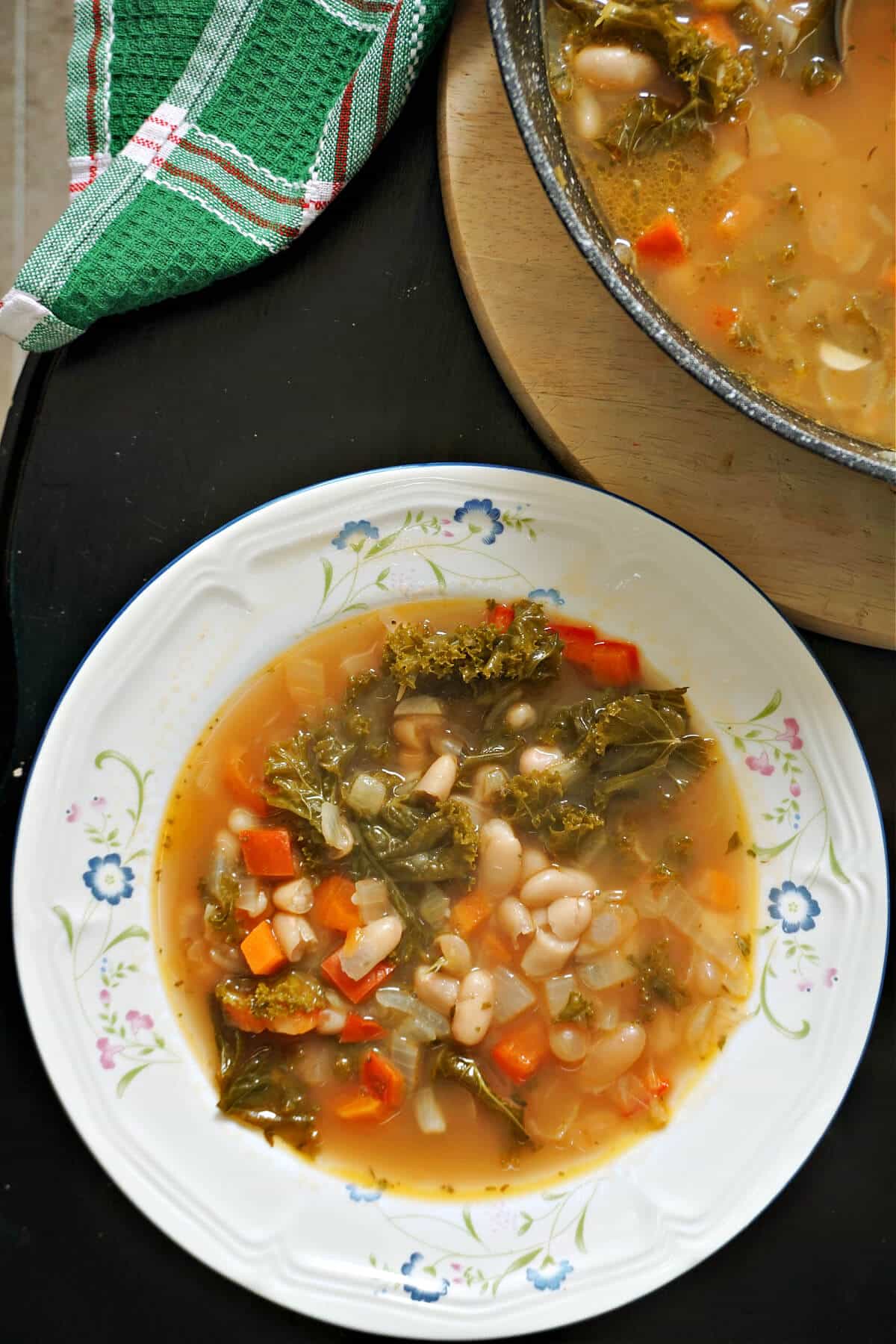 A white plate with kale and white bean soup.