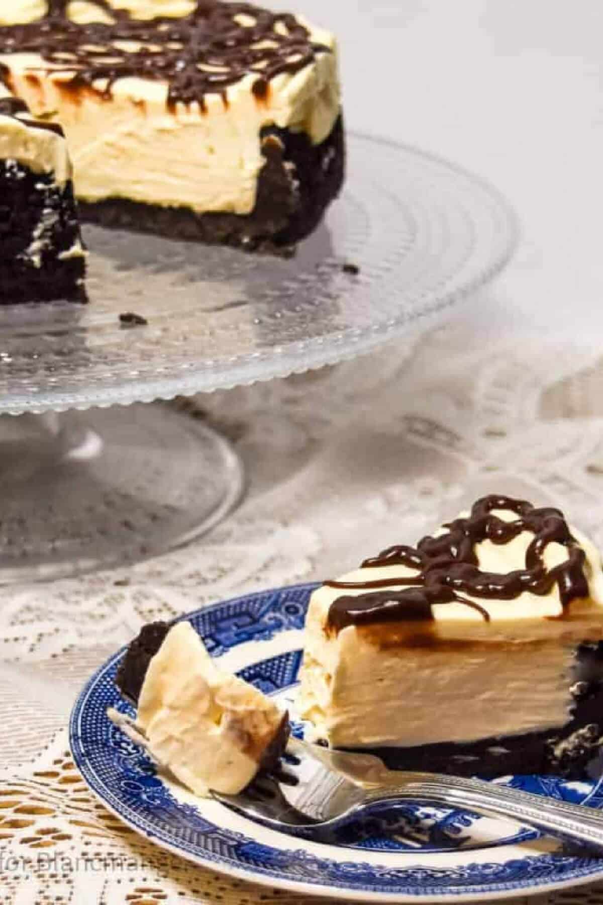 A slice of cheesecake on a plate with the rest of the cake in the background.