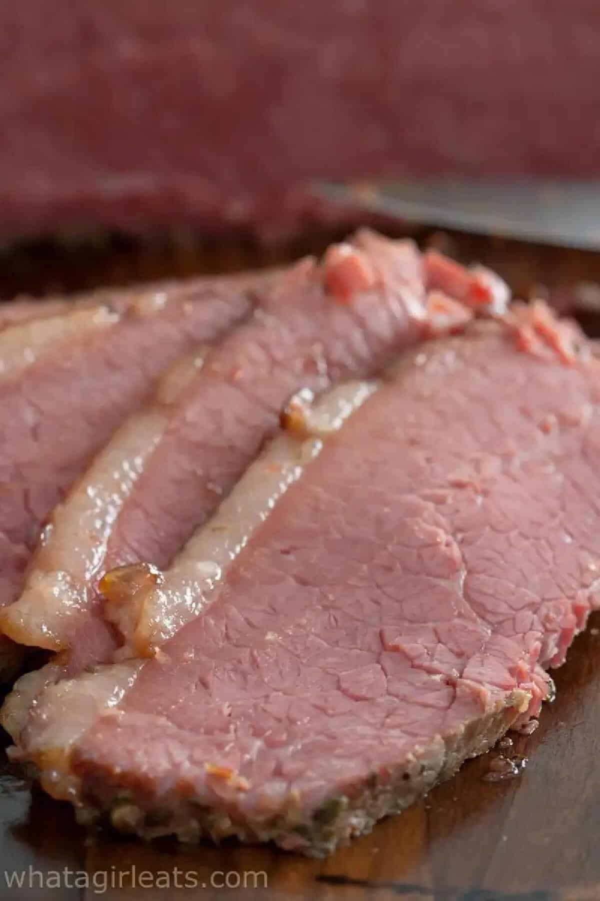 3 slices of corned beef on a wooden board.