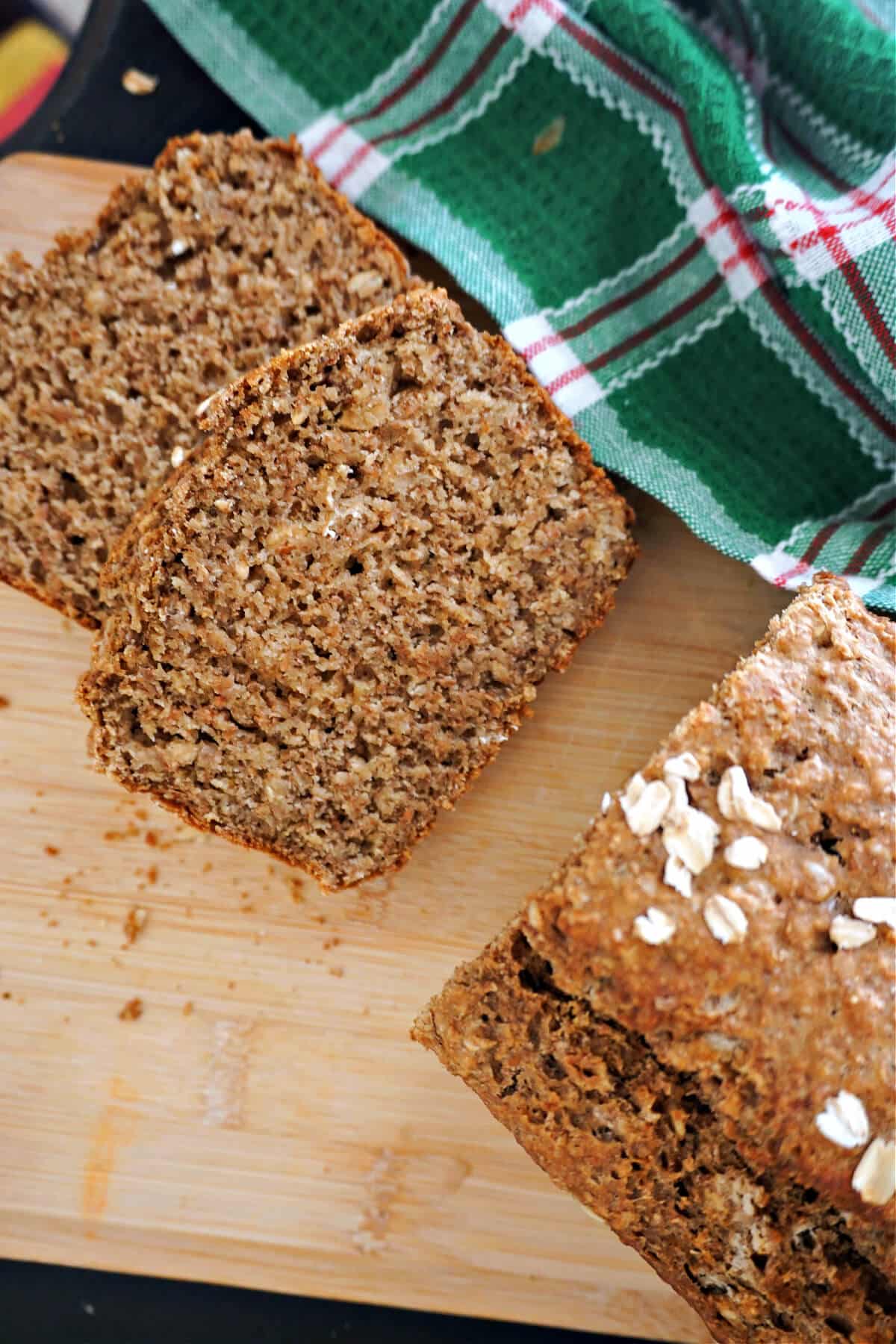 2 slices of brown bread on a wooden board with the rest of the loaf .