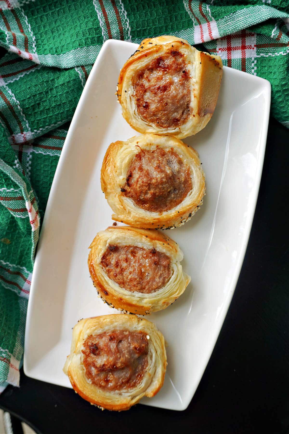 A white rectangle plate with 4 mini sausage rolls.