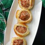 A white plate with 4 mini sausage rolls.