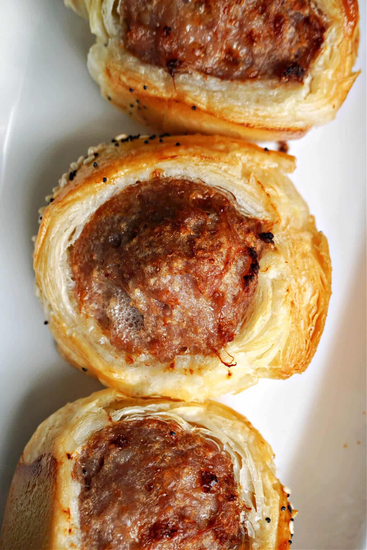 Close-up shot of a sausage roll on a white plate.