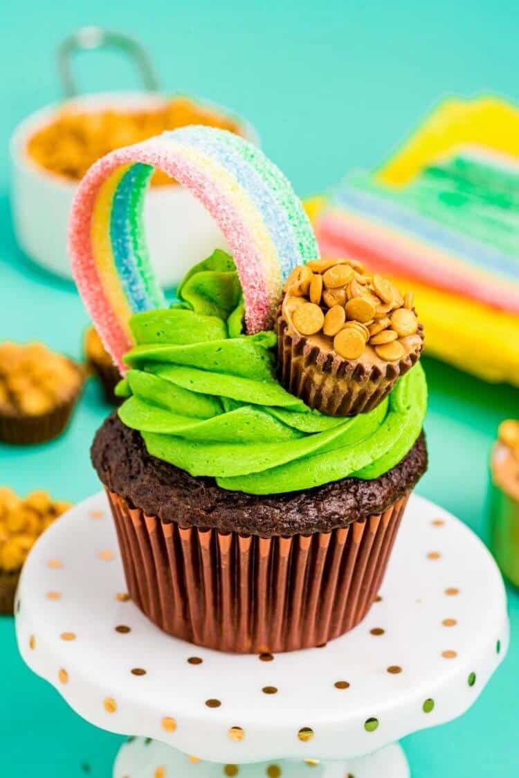 A rainbow cupcake on a white stand.