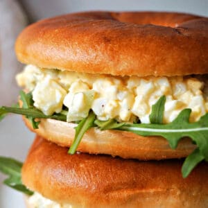 A stack of 2 deviled egg and rocket sandwiches.