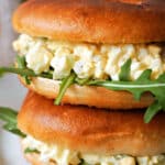 A stack of 2 egg sandwiches with rocket salad.