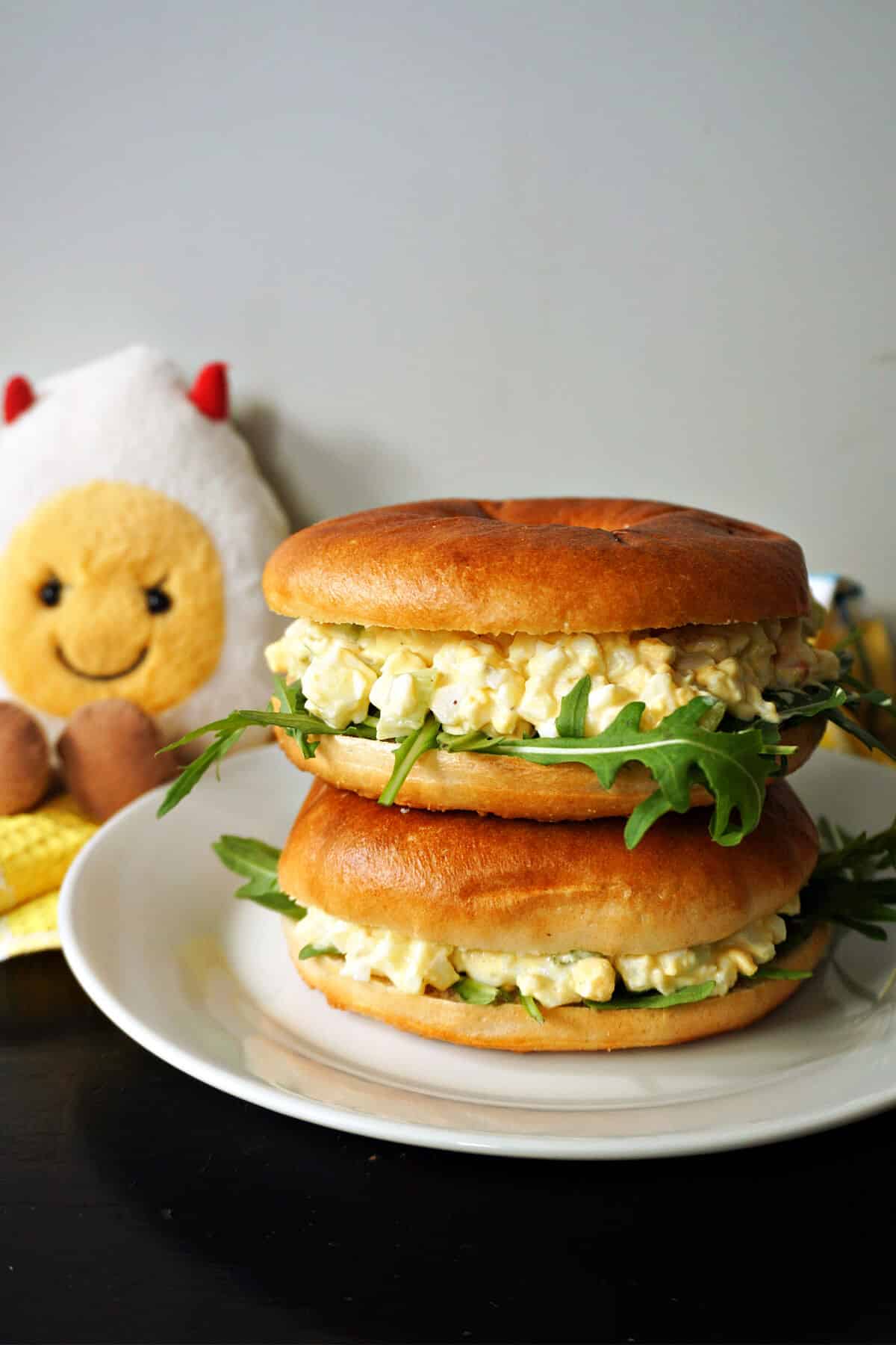 A stack of deviled egg salad sandwiches on a white plate.