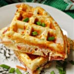 2 waffles on a plate garnished with chopped spring onions.