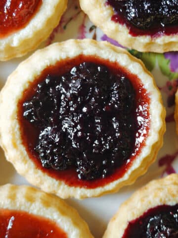 Close-up shoot of a jam tart with other tarts around it.