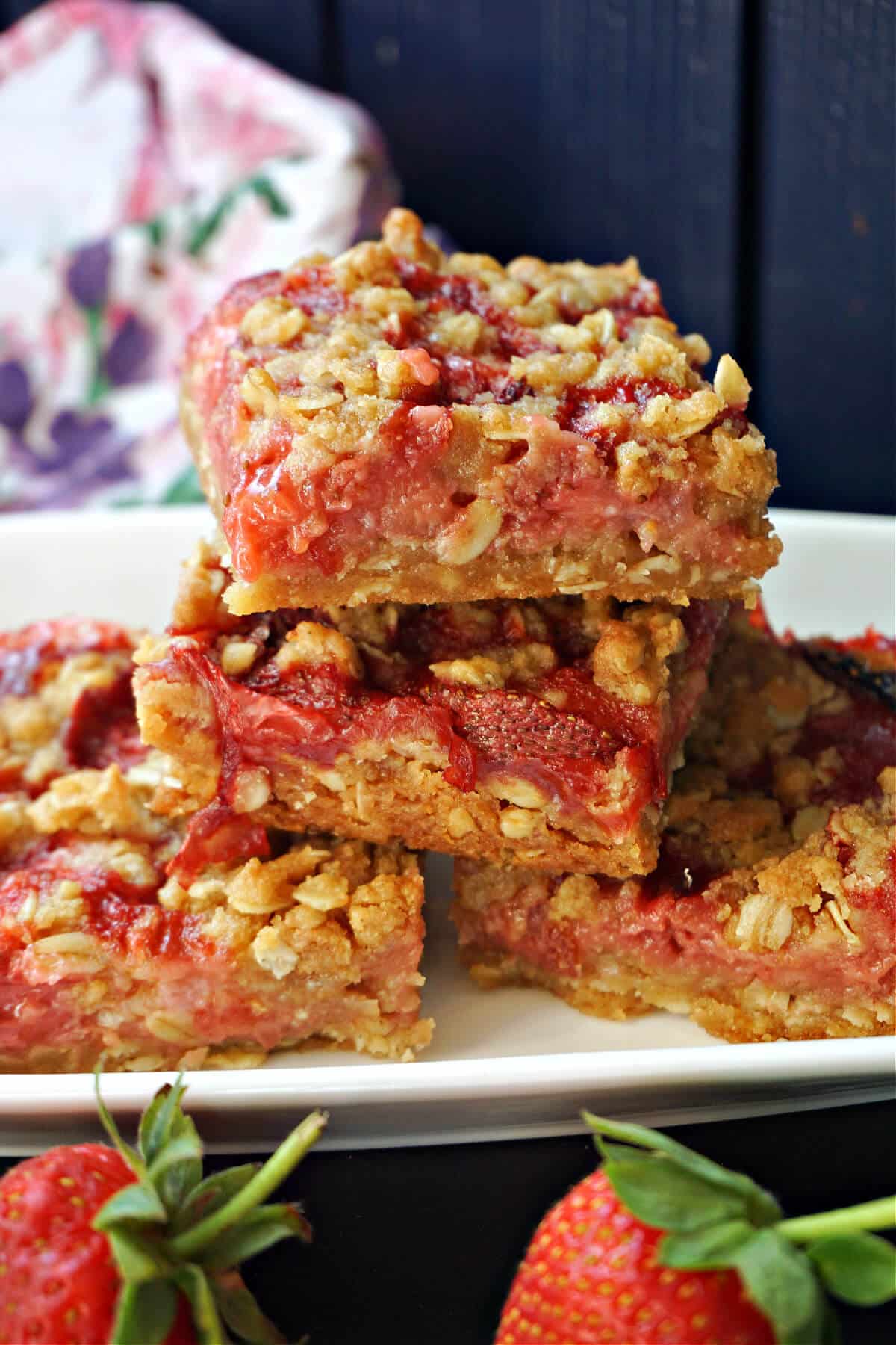 4 strawberry crumble bars on a white rectangle plate.