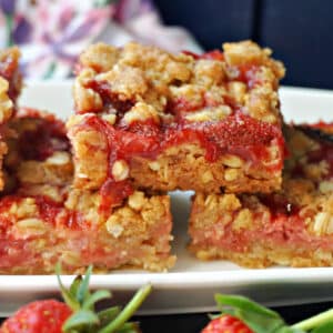 A stack of 3 strawberry crumble bars on a white rectangle plate.