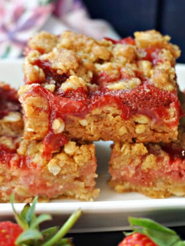 A stack of 3 strawberry crumble bars on a white rectangle plate.
