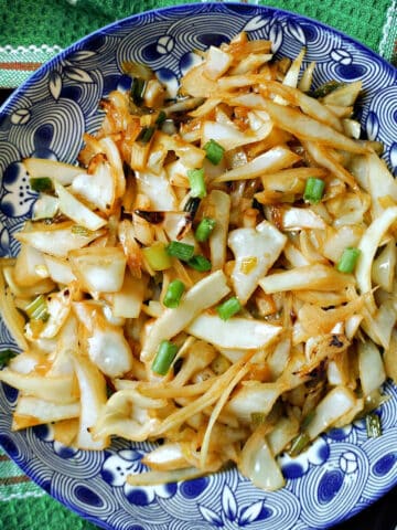 A blue plate with cabbage stir fry.