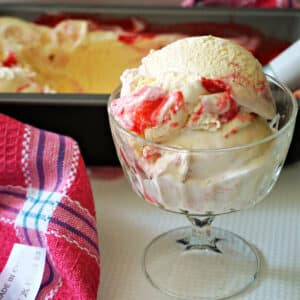 A glass with 2 scoops of clotted cream and raspberry ripple ice cream.