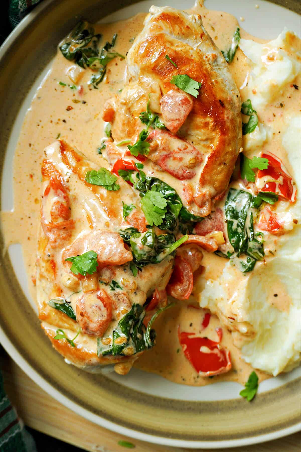 A plate with 2 chicken breasts in a creamy sauce and mash on the side.