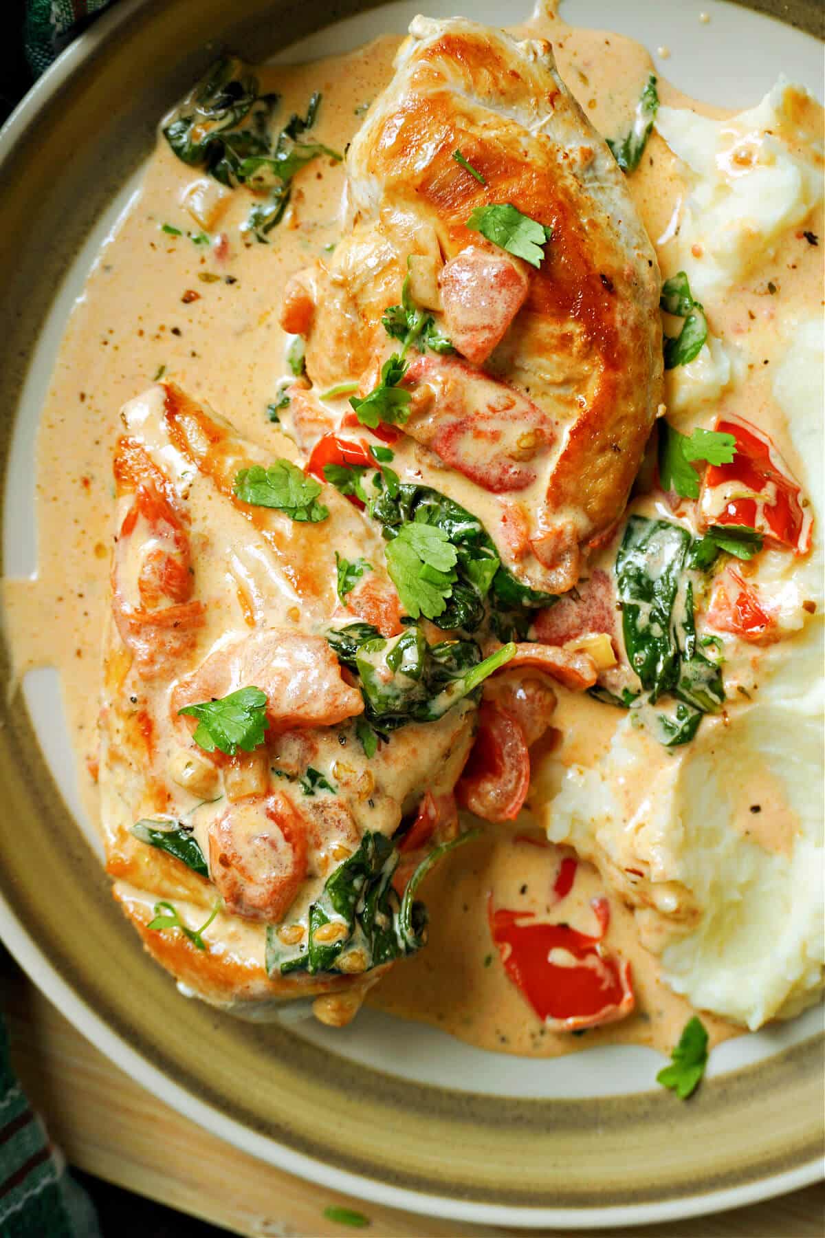 A plate with 2 chicken  breasts in a creamy sauce and mash on the side.