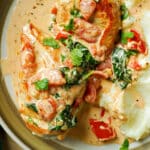 A plate with 2 chicken breasts in a creamy sauce and mashed potatoes.