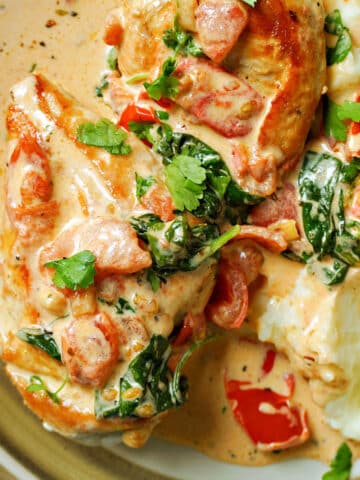 A plate with 2 chicken breasts in a creamy sauce and mashed potatoes.