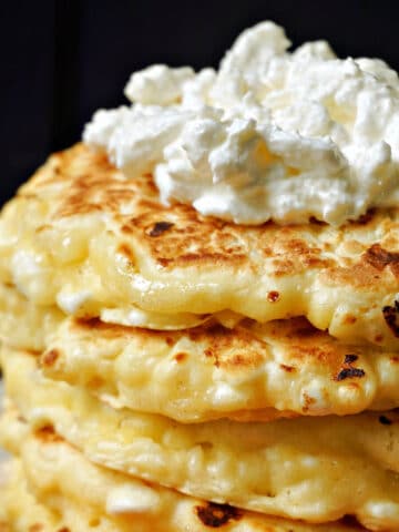 A pile of cottage cheese pancakes with a dollop of cottage cheese inside.