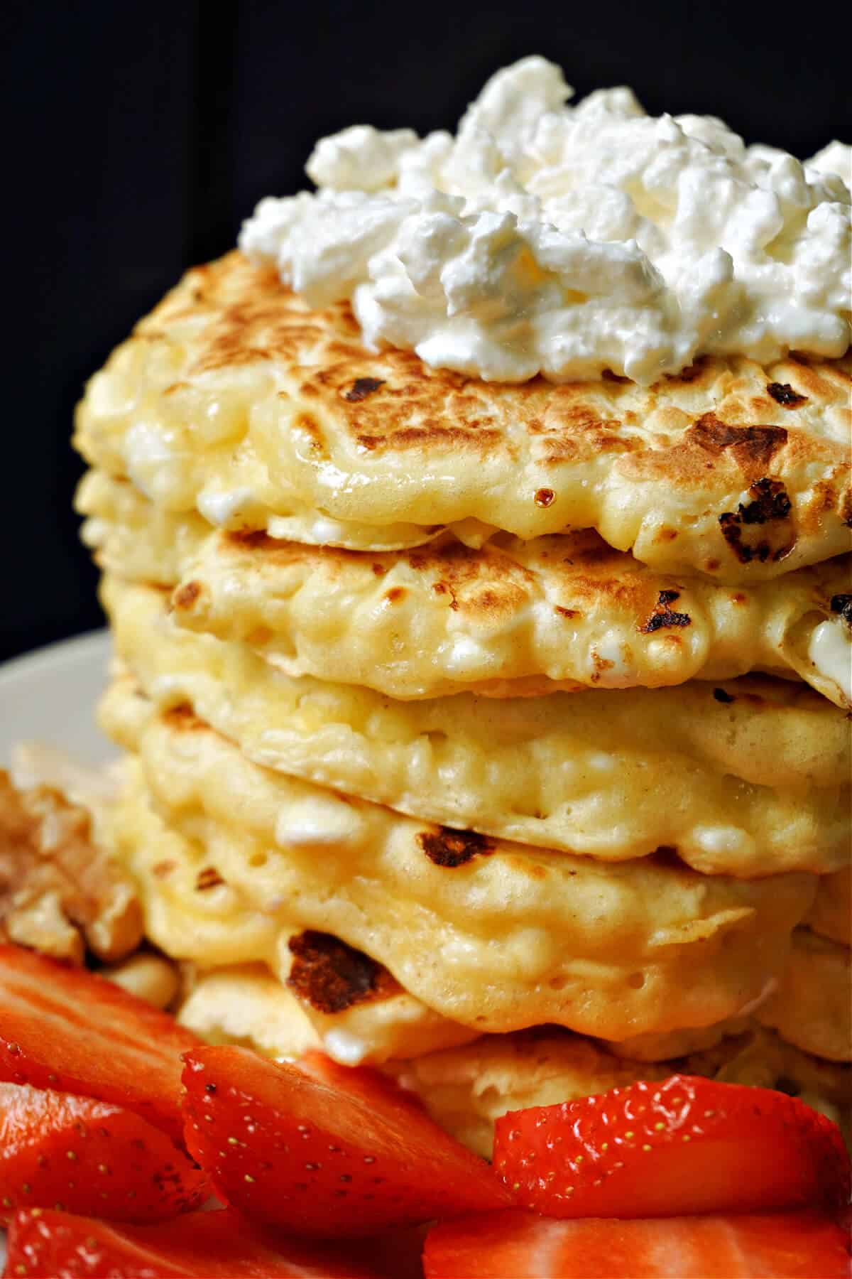 A stack of pancakes topped with cottage cheese.