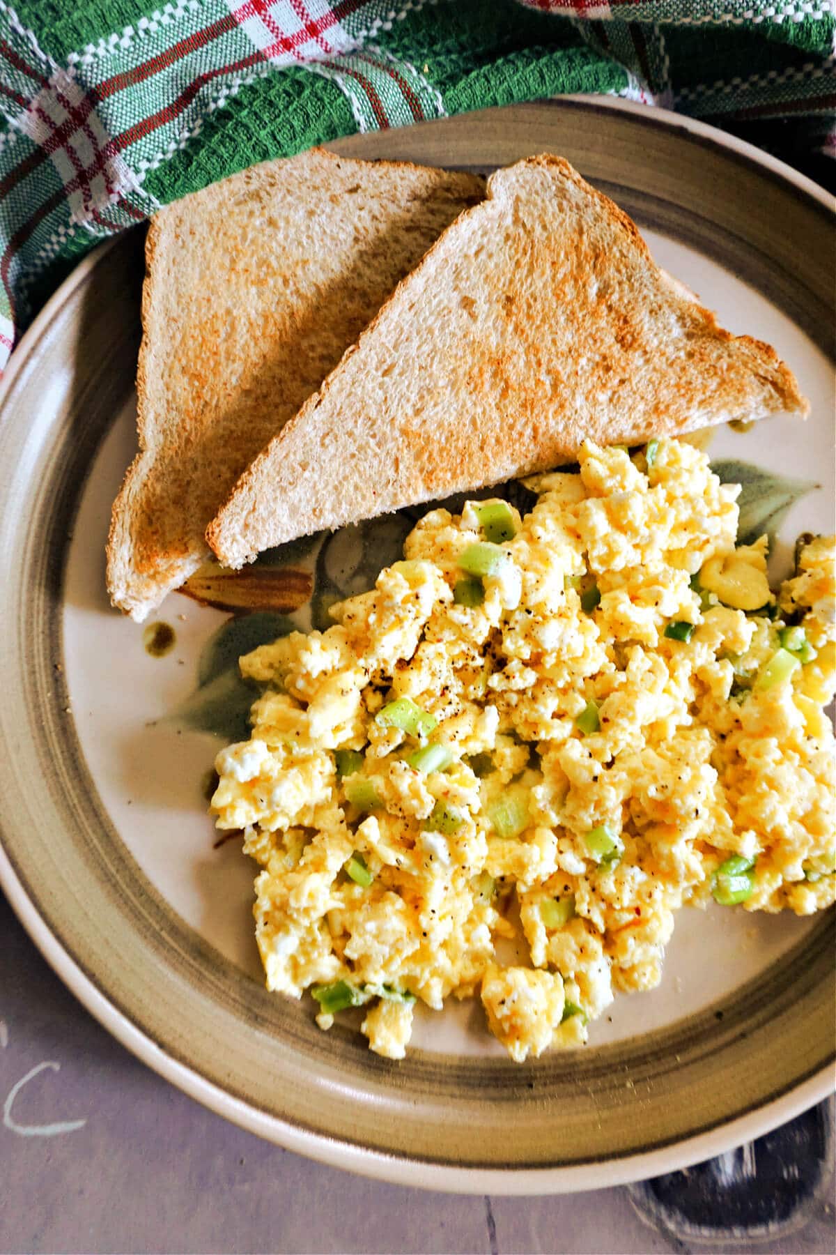 A plate with 2 halves of a toast and scrambled eggs.