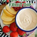 A plate with a small bowl of peanut butter dip and fruit around it.