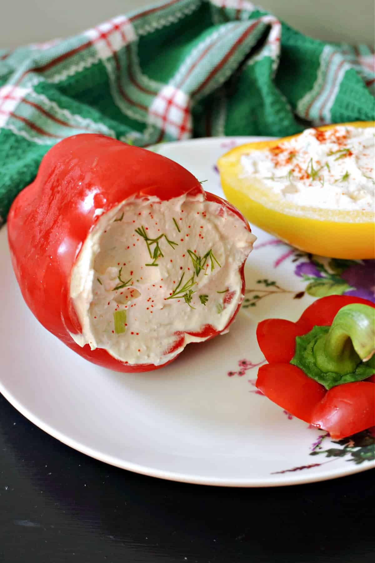 A red pepper stuffed with cheese with another stuffed half yellow pepper in the background.