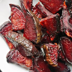 A white plate with roasted beetroot wedges.