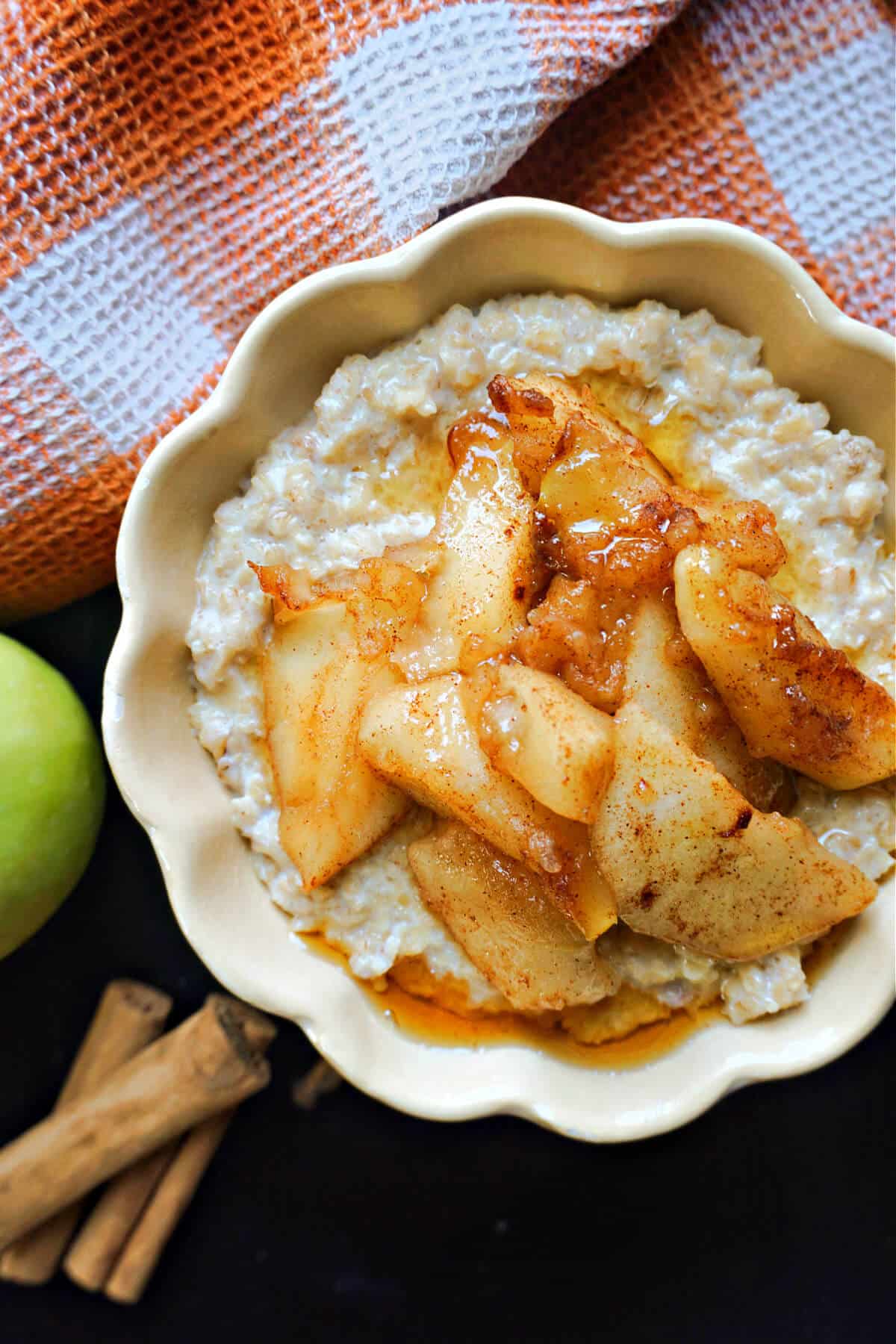 A bowl with porridge topped with apples and a splash of maple syrup.