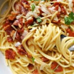 A white plate with garlic bacon pasta.