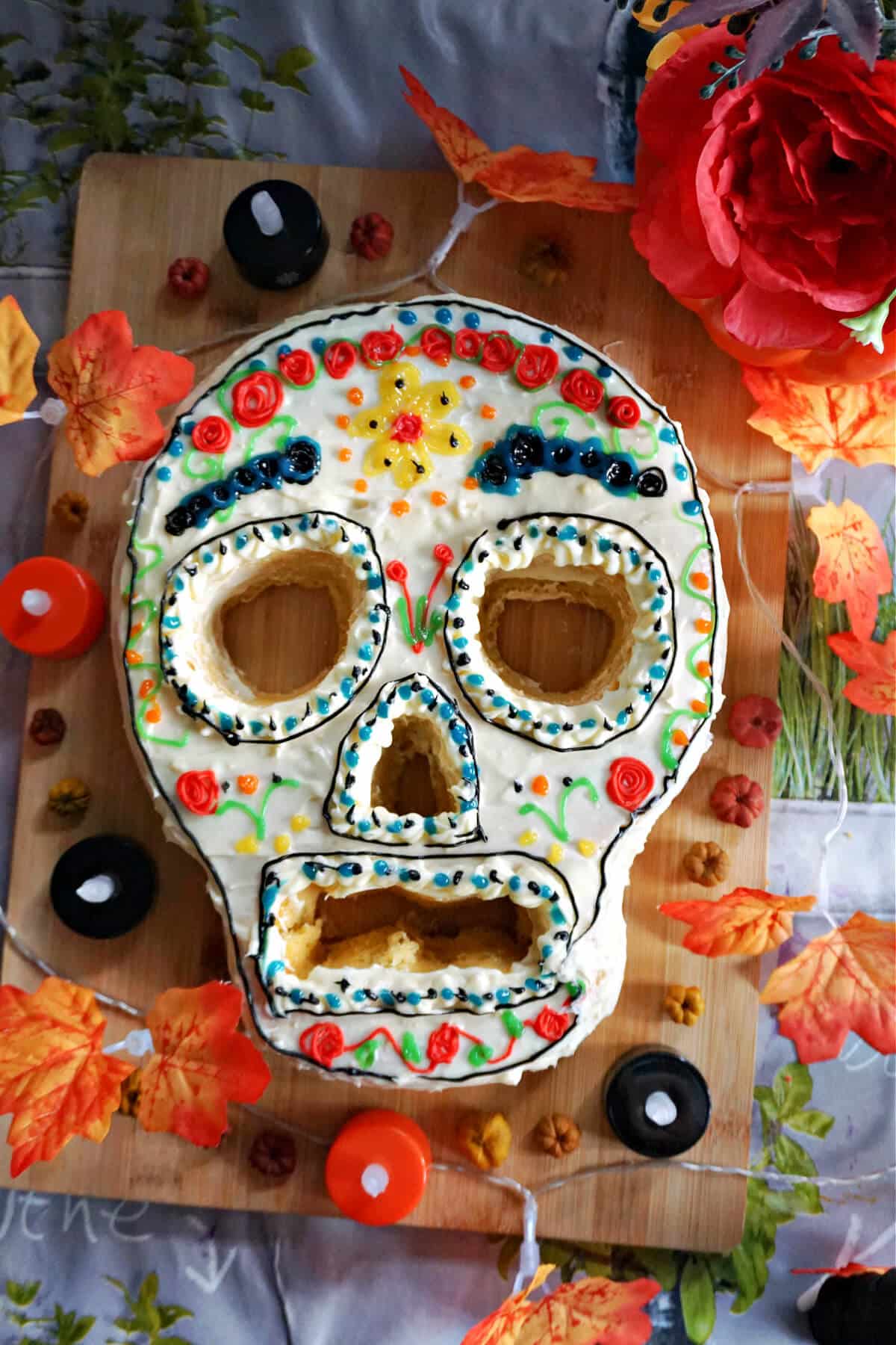 A Day of the Dead Cake on a wooden board with decorations.